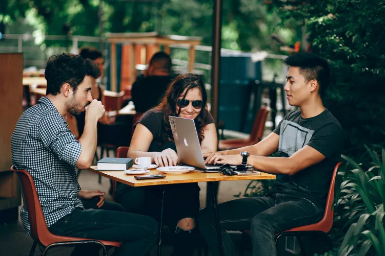 3 people sat in a cafe outside working on laptops