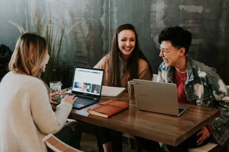 3 people sat around laptops laughing