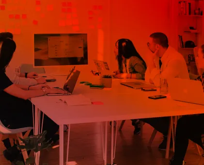 People sat on laptops around a table looking at big screen